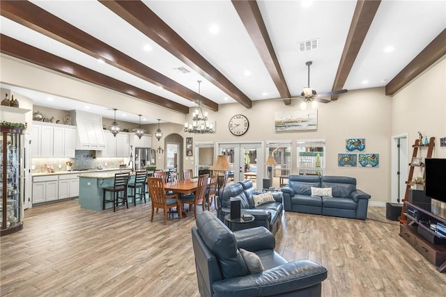 living area with light wood-style flooring, visible vents, arched walkways, and french doors