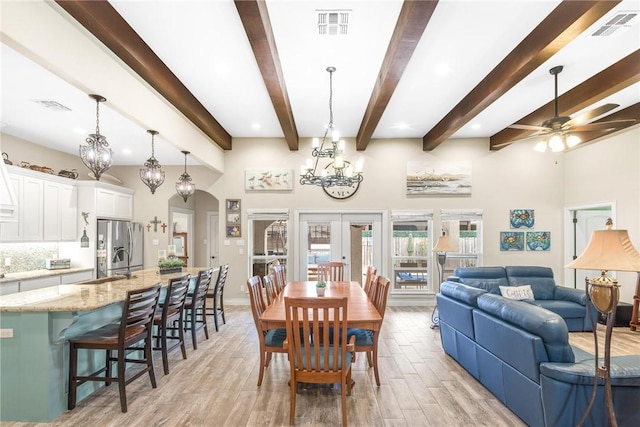 dining area featuring light wood finished floors, visible vents, arched walkways, and french doors