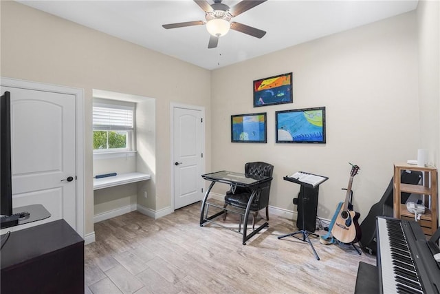 office area with light wood-type flooring, a ceiling fan, and baseboards