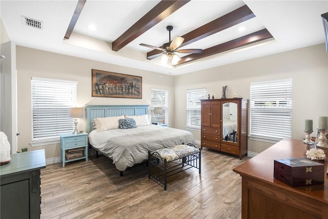 bedroom featuring light wood-style floors, visible vents, and a tray ceiling