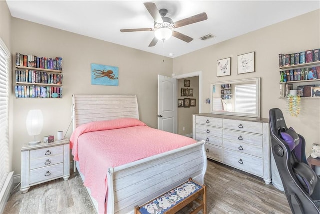 bedroom featuring baseboards, ceiling fan, visible vents, and wood finished floors