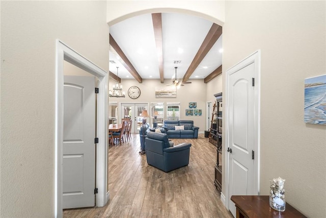 living area with visible vents, arched walkways, beamed ceiling, wood finished floors, and french doors