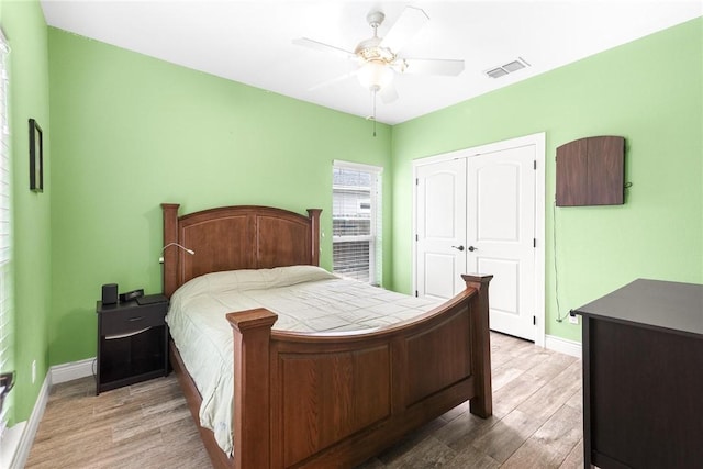 bedroom featuring ceiling fan, visible vents, baseboards, a closet, and light wood finished floors