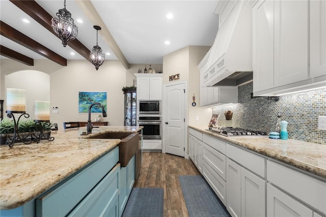 kitchen featuring arched walkways, tasteful backsplash, custom range hood, appliances with stainless steel finishes, and white cabinetry