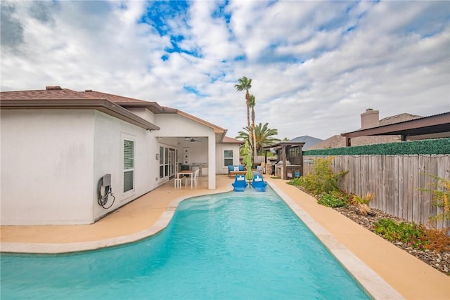 view of swimming pool featuring a patio, fence, a ceiling fan, a fenced in pool, and a pergola