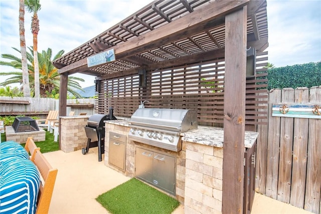 view of patio with fence, an outdoor kitchen, area for grilling, and a pergola