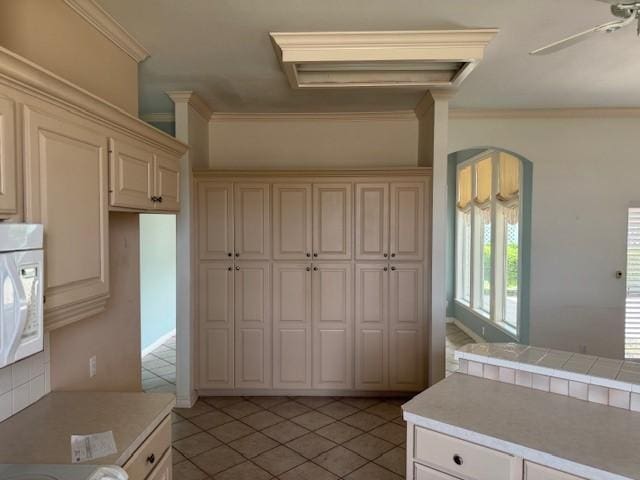 718 Broadway Blvd, Portland, TX 78374 - kitchen featuring white microwave, light tile patterned flooring, cream cabinets, crown molding, and light countertops