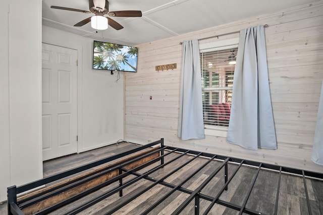 unfurnished bedroom featuring wood walls, ceiling fan, and wood-type flooring