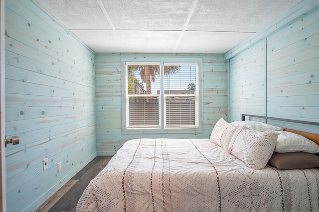 bedroom featuring dark hardwood / wood-style flooring and wooden walls