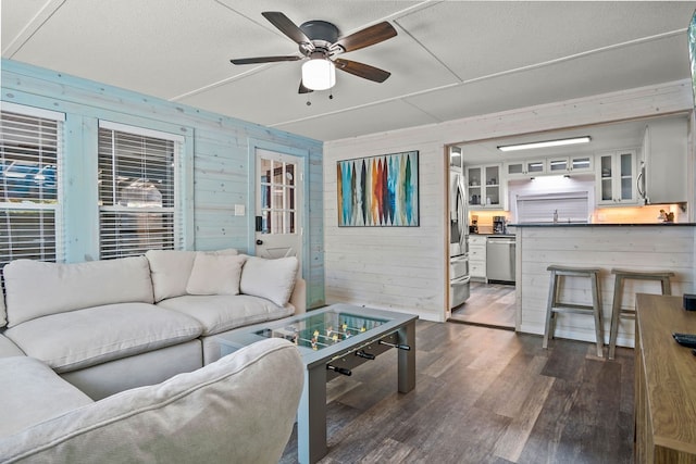 living room with wood walls, sink, dark hardwood / wood-style floors, a textured ceiling, and ceiling fan