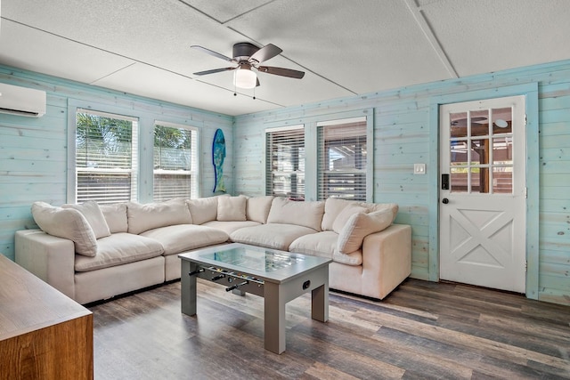 living room featuring dark hardwood / wood-style flooring, wooden walls, and an AC wall unit