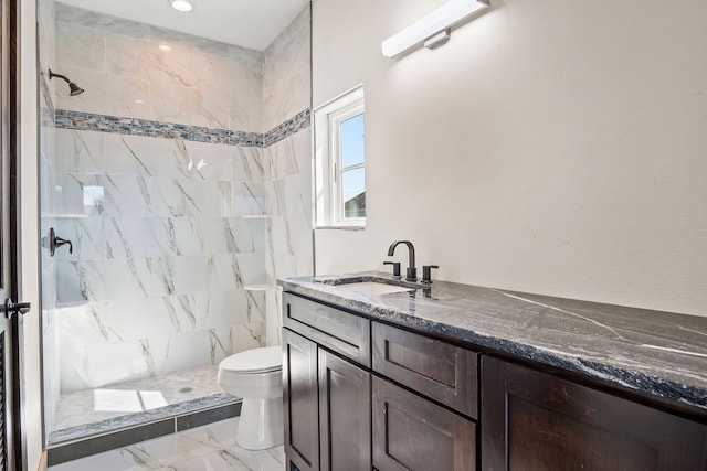 bathroom featuring toilet, vanity, and a tile shower