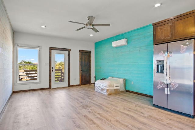 interior space with ceiling fan, stainless steel fridge, light wood-type flooring, and a wall mounted AC