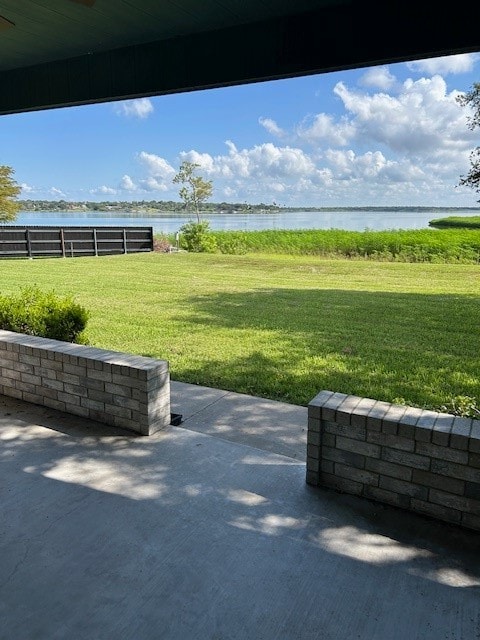 surrounding community with a water view, a patio area, and a lawn