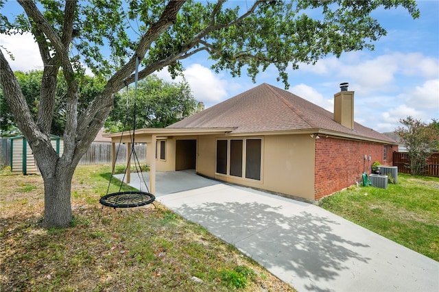 rear view of property featuring central AC unit, a lawn, and a patio