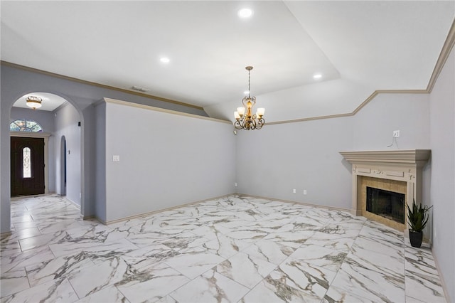 unfurnished living room with ornamental molding, a tiled fireplace, and a notable chandelier