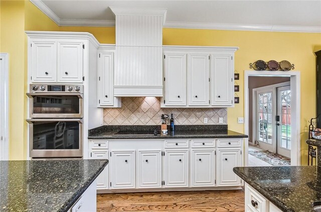 5918 Woodmere Dr, Corpus Christi, TX 78414 - kitchen with stainless steel double oven, white cabinetry, ornamental molding, backsplash, and dark stone counters