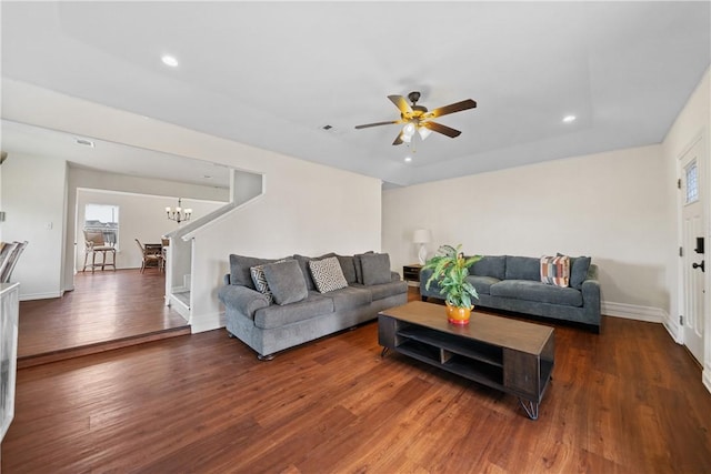 living room featuring dark wood-type flooring and ceiling fan with notable chandelier