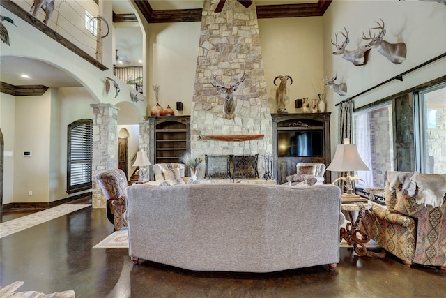 living room with beamed ceiling, a stone fireplace, a towering ceiling, and decorative columns