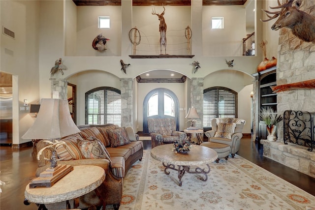 living room with hardwood / wood-style floors, a fireplace, a high ceiling, and decorative columns