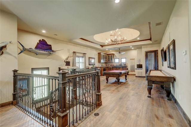 recreation room featuring hardwood / wood-style floors, a raised ceiling, pool table, and a chandelier