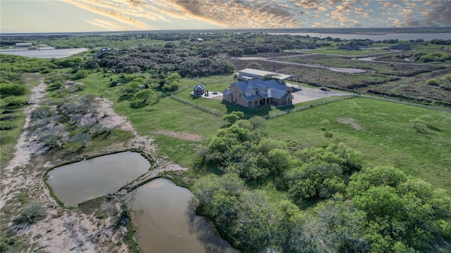 aerial view at dusk featuring a rural view and a water view