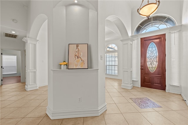 tiled foyer entrance with a high ceiling and decorative columns