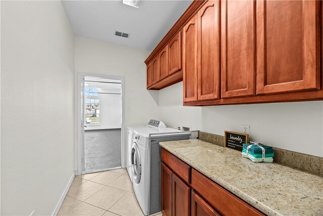 laundry area featuring light tile patterned flooring, cabinets, and washing machine and clothes dryer