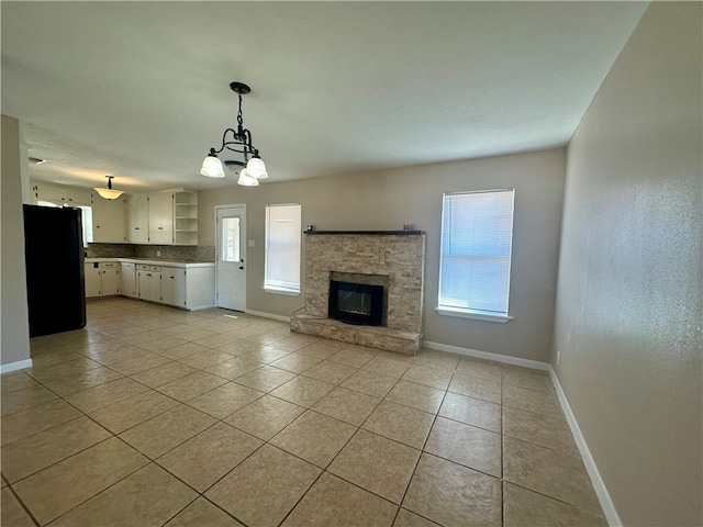 unfurnished living room featuring a fireplace, light tile patterned floors, and an inviting chandelier