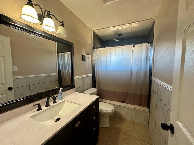 full bathroom featuring tile patterned flooring, toilet, shower / bath combo with shower curtain, vanity, and tile walls