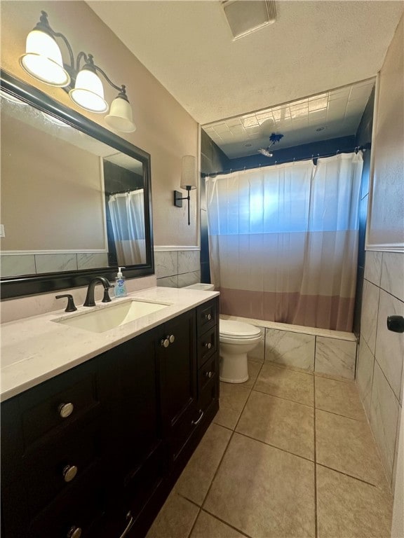 full bathroom with shower / bath combo, tile patterned floors, toilet, vanity, and tile walls