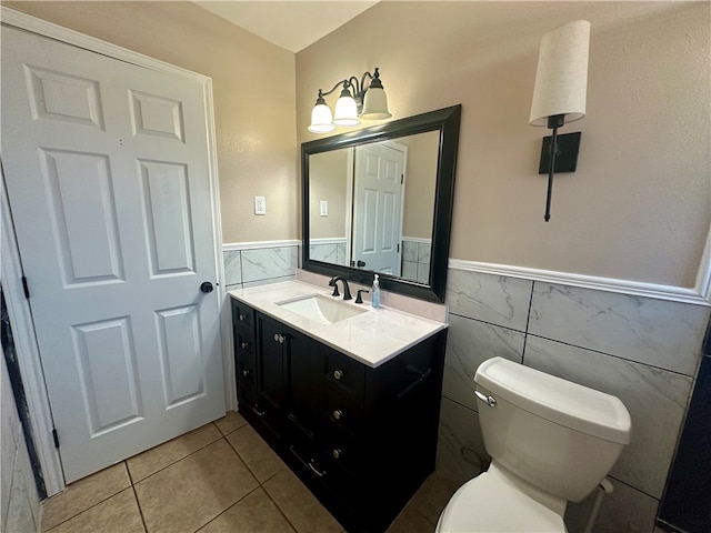 bathroom featuring vanity, tile patterned flooring, toilet, tile walls, and a chandelier