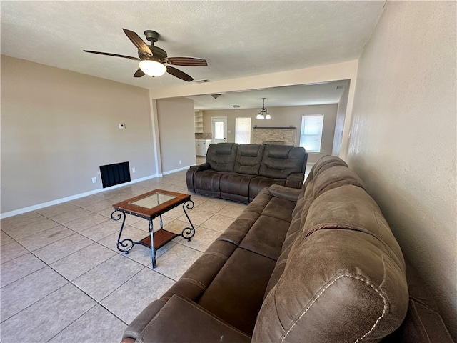 living room featuring light tile patterned floors, a textured ceiling, and ceiling fan