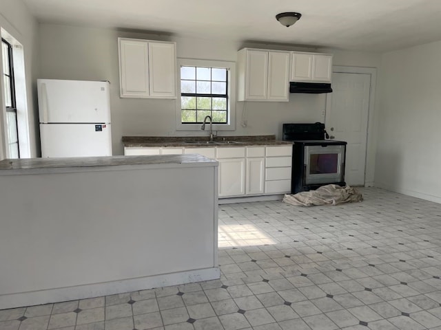 kitchen with stove, sink, white fridge, and white cabinets