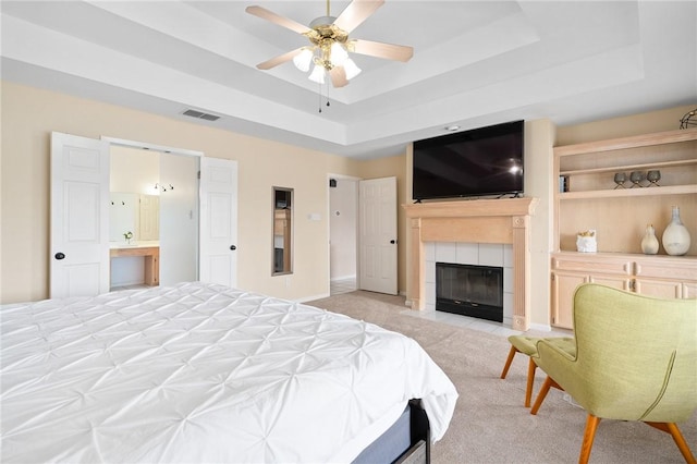 1025 Pompano Dr, Aransas Pass, TX 78336 - bedroom with a raised ceiling, light colored carpet, a tile fireplace, and ceiling fan