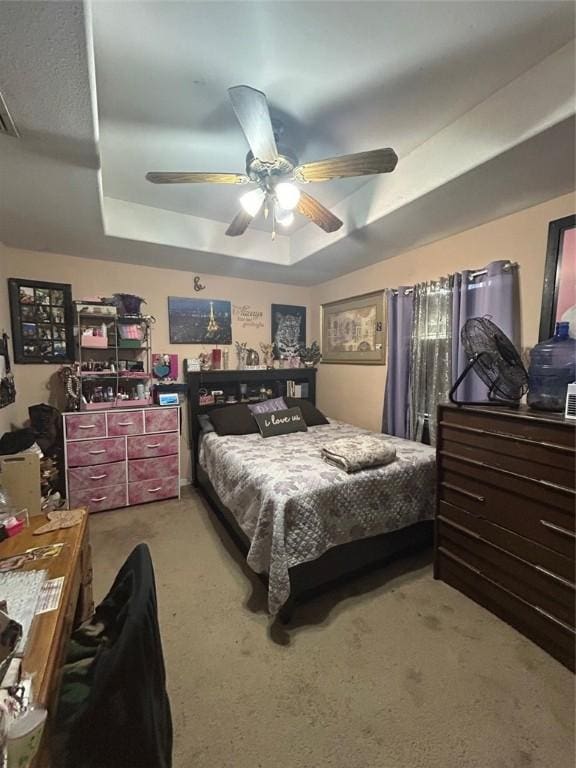 carpeted bedroom with a tray ceiling and ceiling fan