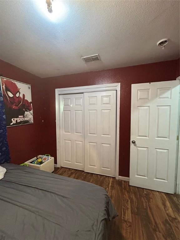 bedroom with dark hardwood / wood-style floors, a textured ceiling, and a closet