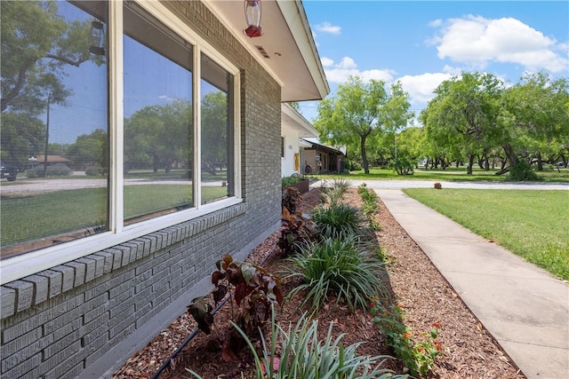 view of property exterior with brick siding and a yard