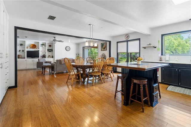 dining space featuring beamed ceiling, light wood-style floors, visible vents, and a healthy amount of sunlight