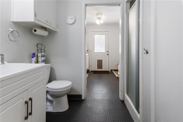 bathroom with a shower stall, toilet, vanity, and tile patterned floors
