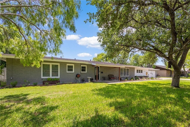 back of house with a yard, a patio area, driveway, brick siding, and a garage
