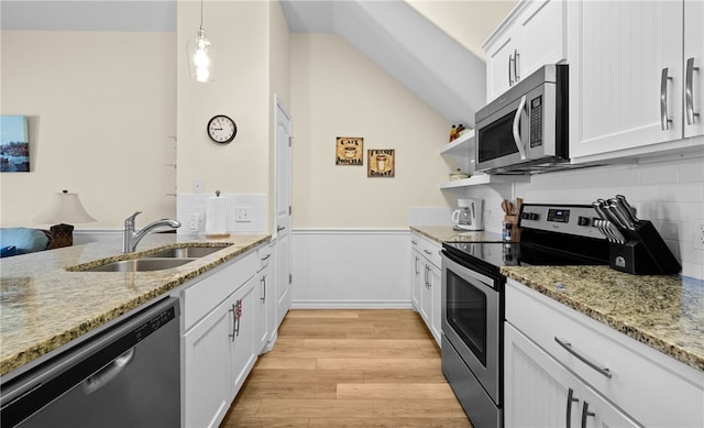 kitchen with stainless steel appliances, white cabinetry, decorative light fixtures, sink, and light hardwood / wood-style floors