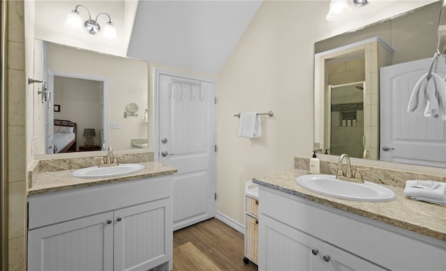 bathroom with a shower with door, vanity, hardwood / wood-style flooring, and vaulted ceiling