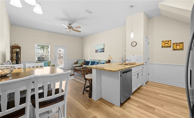 kitchen with light hardwood / wood-style floors, dishwasher, white cabinets, a breakfast bar area, and decorative light fixtures