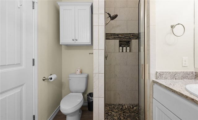 bathroom featuring a tile shower, vanity, and toilet