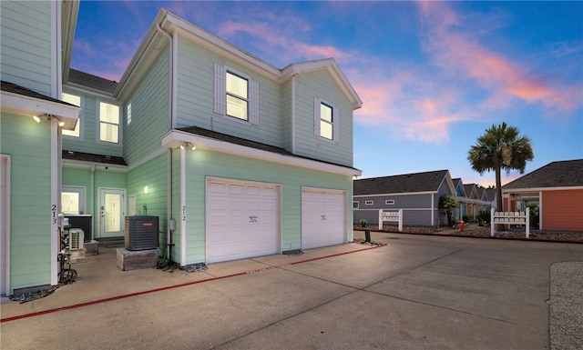 property exterior at dusk featuring central air condition unit and a garage