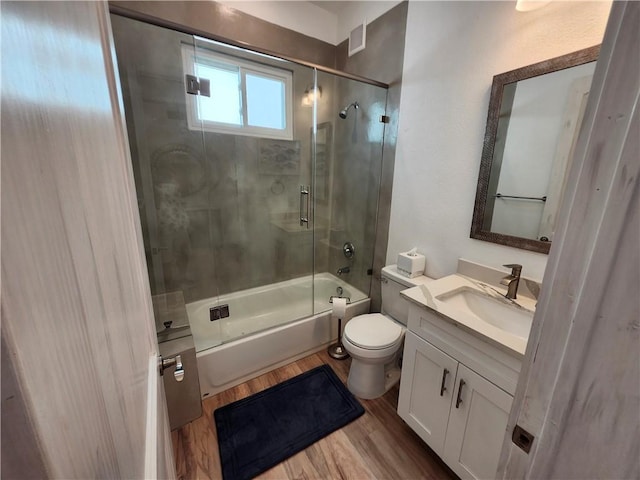 bathroom featuring combined bath / shower with glass door, vanity, toilet, and wood finished floors