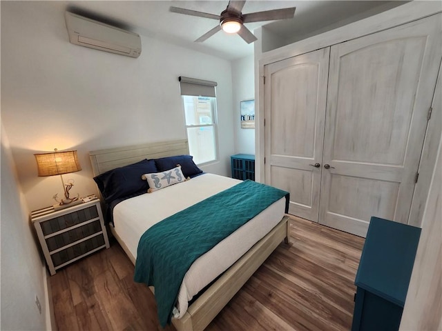 bedroom with ceiling fan, a closet, a wall unit AC, and wood finished floors