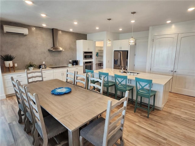 dining room featuring light wood finished floors, a wall unit AC, and recessed lighting