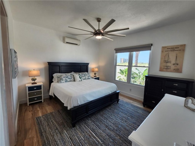 bedroom with ceiling fan, dark wood-style flooring, a wall unit AC, and baseboards